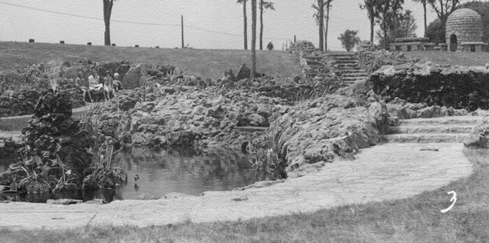 Minnesota Highway Department, 1940 Shows Graeser Park in 1940 with its cone-shaped fountain on the left with pond in foreground and waterfall wall behind. Children are sitting in one of the benches built into the rock wall. The rock garden path and steps lead up to the beehive fireplace and picnic tables.