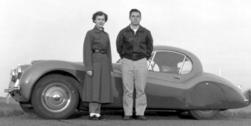 Young woman and man by 1952 Jaguar automobile